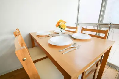 a wooden table with white plates and flowers on it at Full facilities 9PPL CozyHouse1 stop-Yamanote Line in Tokyo