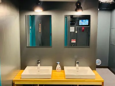 two sinks in a public restroom with two mirrors at Hinode Kagurazakaekimae Hotel in Tokyo