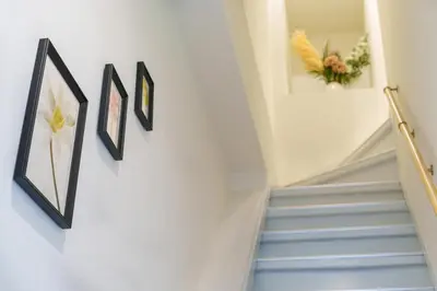a stairway with three pictures on the wall and blue stairs at \u6953\u5c4b\u30a2\u30cd\u30c3\u30af\u30b9 120Tb in Tokyo