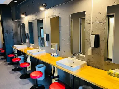 a bathroom with three sinks and red stools at Mikami Asakusabashi Hotel in Tokyo