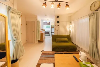 a living room with a green couch and a clock at \u697d\u5bbfSUMIDA 002t in Tokyo