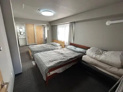 a room with three beds and a window at Haneda Base in Tokyo