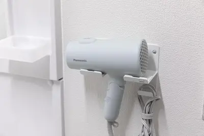 a white hair dryer hanging from a wall at Y's INN 駒込 110T in Tokyo