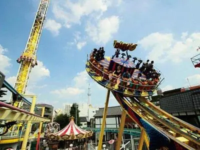 a group of people riding on a ride at a carnival at \u4e09\u30ce\u8f2a401 in Tokyo