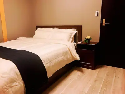 a bedroom with a bed with white sheets and a wooden floor at \u4e09\u30ce\u8f2a401 in Tokyo