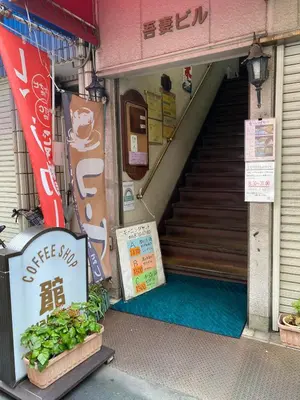 a store entrance with a sign in front of a stairs at \u697d\u5bbf \u4e2d\u4e95 004t in Tokyo