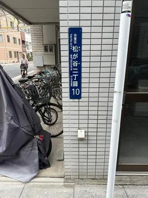 a blue sign on the side of a building with bikes at \u53f0\u4e1c\u533a\u677e\u8c37 in Tokyo