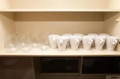 a row of white glasses sitting on a shelf at Y's INN 有客 015T in Tokyo