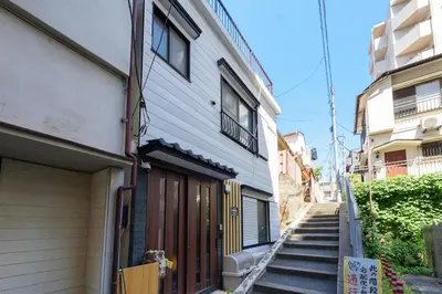 a building with a garage and stairs next to a house at \u697d\u9038\u30b0\u30eb\u30fc\u30d7 \u65b0\u5bbf\u5fa1\u82d1 112t in Tokyo