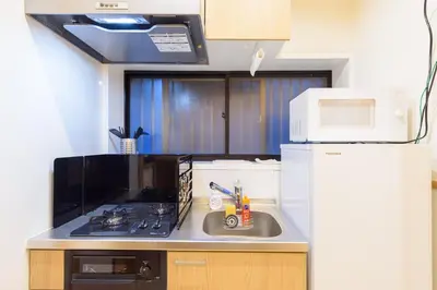 a kitchen with a sink and a stove and a microwave at \u697d\u9038\u30b0\u30eb\u30fc\u30d7 \u65b0\u5bbf\u5fa1\u82d1 112t in Tokyo