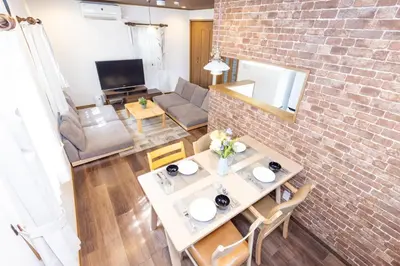 a living room with a table and a brick wall at Y's INN Tsutusji 014T in Tokyo