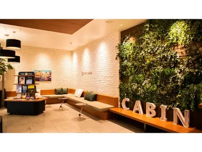 a lobby with a couch and a large green wall at First Cabin Ichigaya 
