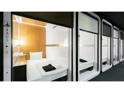 a small room with a bed and some mirrors at First Cabin Ichigaya 