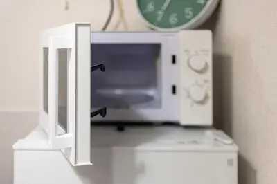 a microwave sitting on top of a counter with a clock at Y's INN Nakano 016T in Tokyo