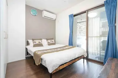 a bedroom with a bed with blue curtains and a window at W Haus \u6771\u4eac\u6674\u7a7a\u5854\u8def\u7a0b3\u5206 \u6d45\u8349\u5bfa\u8def\u7a0b10\u5206 \u8d85\u5927\u7a7a\u95f4\u72ec\u680b\u522b\u5885 \u6700\u591a11\u4f4d\u5165\u4f4f in Tokyo