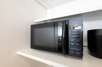 a black microwave oven sitting on a shelf at FINOA Asakusa Sky Terrace in Tokyo