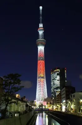 a tall tower lit up in red and white at night at rd\u6c11\u6cca2F in Tokyo