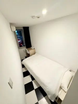 a small bedroom with a bed and a checkered floor at DesignAward,Alphinaud in Tokyo