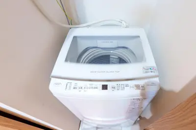 a white washing machine in a corner of a room at Y's INN Ikefukuro 109T in Tokyo