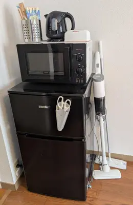a microwave sitting on top of a refrigerator at Nomado Base at YOYOGI in Tokyo