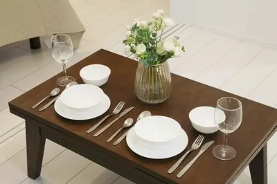 a table with white plates and silverware and a vase of flowers at ALDO INN Toyosu in Tokyo