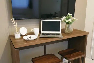 a laptop computer sitting on top of a wooden desk at ALDO INN Toyosu in Tokyo