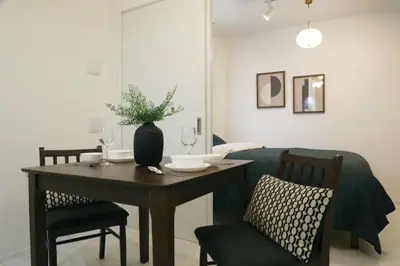 a dining room table and chairs with a vase on it at ALDO INN Toyosu in Tokyo