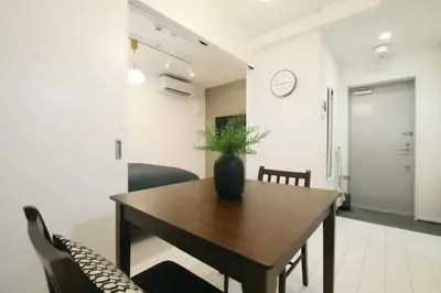 a dining room with a table and chairs and a clock at ALDO INN Toyosu in Tokyo