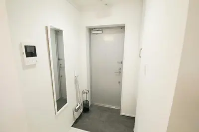 a white bathroom with a mirror and a door at ALDO INN Toyosu in Tokyo