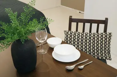 a wooden table with plates and glasses and a vase at ALDO INN Toyosu in Tokyo