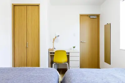 a bedroom with two beds and a desk with a yellow chair at \u697d\u5bbf Nishi Shinjuku 017T in Tokyo