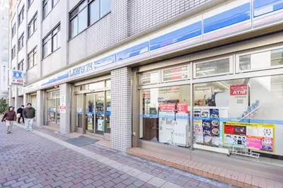 two people walking down a street in front of a store at \u697d\u5bbf Nishi Shinjuku 017T in Tokyo