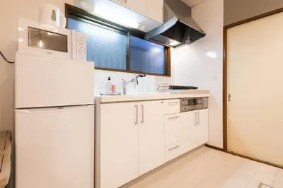 a kitchen with white cabinets and a white refrigerator at Y's INN Koiwa 010T in Tokyo