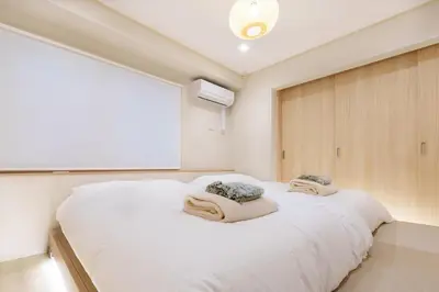 a bedroom with a white bed with two towels on it at \u697d\u9038\u30b0\u30eb\u30fc\u30d7 \u6c60\u888b\u745e\u6708\u82d11F 111Ta in Tokyo