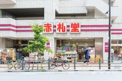 a woman walking with an umbrella in front of a store at \u697d\u9038\u30b0\u30eb\u30fc\u30d7 \u6c60\u888b\u745e\u6708\u82d12F 111Tb in Tokyo