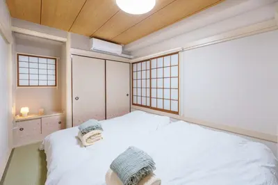a bedroom with a white bed with two towels on it at \u697d\u9038\u30b0\u30eb\u30fc\u30d7 \u6c60\u888b\u745e\u6708\u82d12F 111Tb in Tokyo