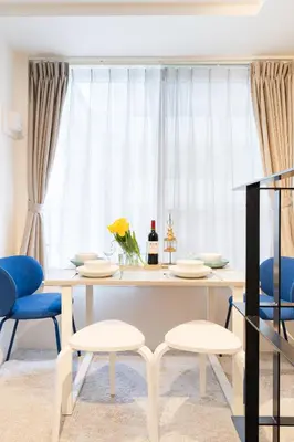 a dining room with a white table and blue chairs at T r u s t V a l u e Kuramae in Tokyo