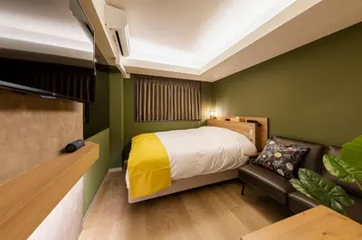 a bedroom with green walls and a bed and a couch at Hotel The Loop in Tokyo