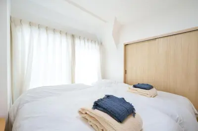 a bedroom with a white bed with towels on it at \u697d\u9038\u30b0\u30eb\u30fc\u30d7 \u6c60\u888b\u745e\u6708\u82d13F 111Tc in Tokyo