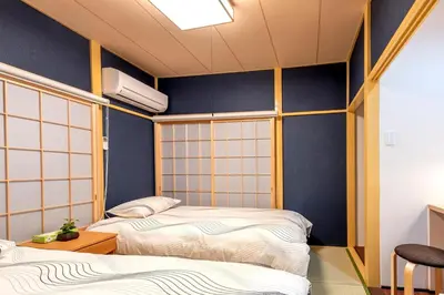 two beds in a room with blue walls at Y's INN MaisonRose 106T in Tokyo