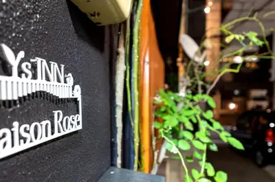 a sign on the side of a building with a plant at Y's INN MaisonRose 106T in Tokyo