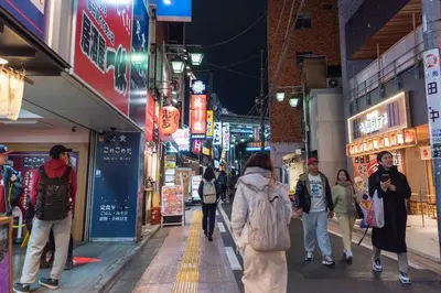 a group of people walking down a street at night at Y's INN MaisonRose 106T in Tokyo