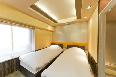 two beds in a room with a window at International Hotel Kabukicho in Tokyo