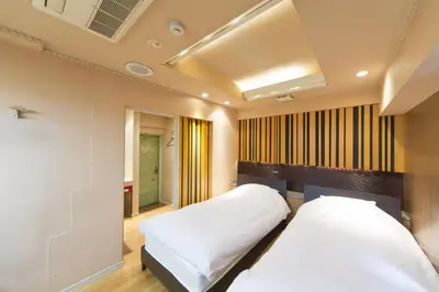 a bedroom with two beds and a ceiling at International Hotel Kabukicho in Tokyo