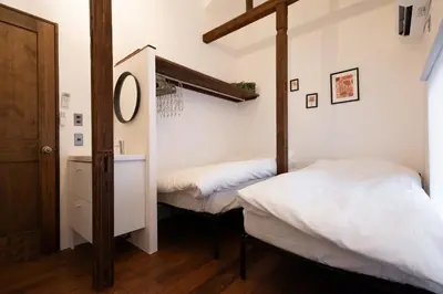 two beds in a room with white walls and wooden floors at \u30ca\u30ab\u30ce\u30b3\u30df\u30c1 Nakanokomichi in Tokyo