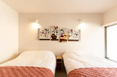 two beds in a room with white walls at \u51ea\u30ce\u5bb6\u66f3\u821f Naginoya Hikihune in Tokyo
