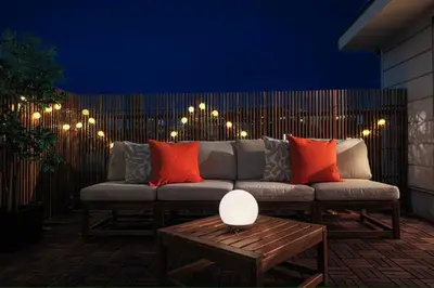 a couch on a patio with lights on a fence at \u51ea\u30ce\u5bb6\u66f3\u821f Naginoya Hikihune in Tokyo