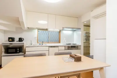 a kitchen with white cabinets and a wooden table at \u6c60\u888b\u65b0\u5bbf\u30a8\u30ea\u30a2 \u5927\u585a\u99c5\u8fd1 \u5546\u5e97\u8857\u5f92\u6b69\u570f\u5185 \u8cb8\u5207\u4e00\u6238\u5efa 2\u90e8\u5c4b \u6700\u59275\u540d\u5bbf\u6cca\u53ef in Tokyo
