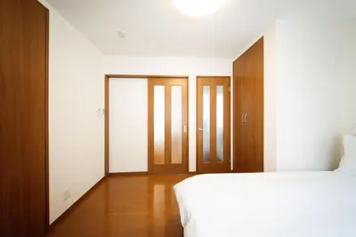 a bedroom with a bed and wooden doors at \u6c60\u888b\u65b0\u5bbf\u30a8\u30ea\u30a2 \u5927\u585a\u99c5\u8fd1 \u5546\u5e97\u8857\u5f92\u6b69\u570f\u5185 \u8cb8\u5207\u4e00\u6238\u5efa 2\u90e8\u5c4b \u6700\u59275\u540d\u5bbf\u6cca\u53ef in Tokyo