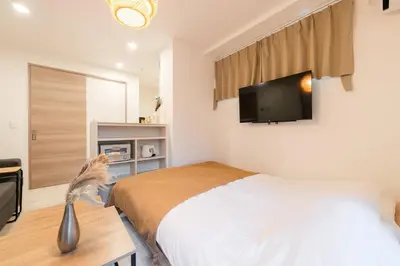 a bedroom with a bed and a tv on the wall at House Hotel EKODA 2F HE2122 in Tokyo